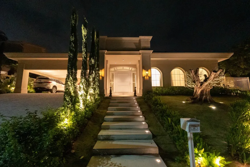 Residência iluminada à noite com paisagismo