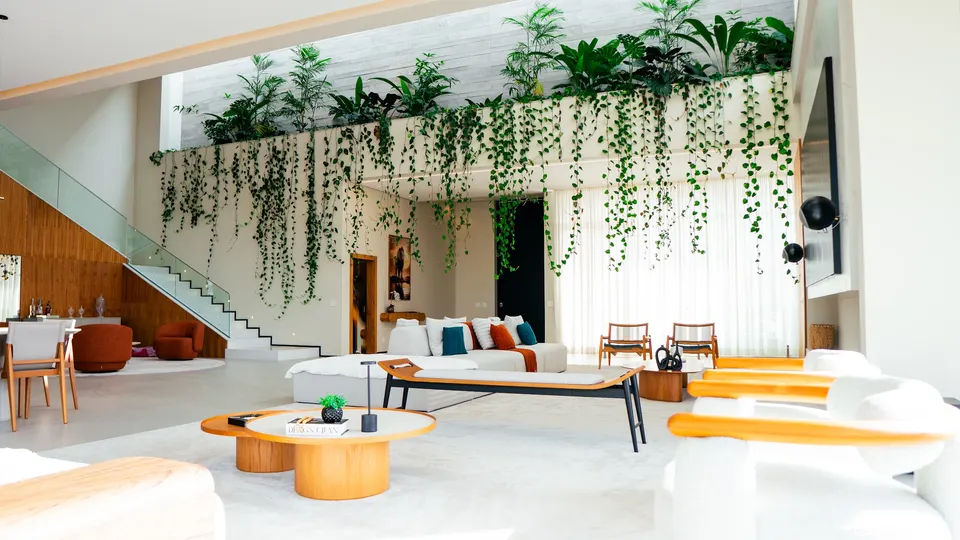 Living amplo com vegetação suspensa e luz natural